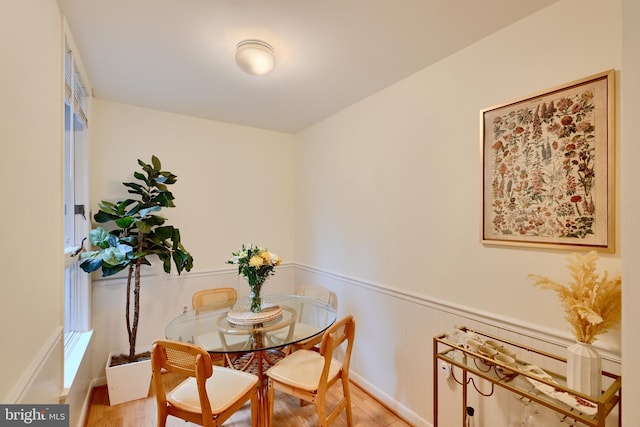 dining room featuring a wainscoted wall and light wood-style flooring