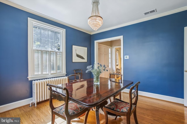 dining room with light wood-style flooring, baseboards, radiator, visible vents, and a chandelier