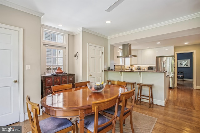dining room featuring recessed lighting, a toaster, baseboards, crown molding, and wood finished floors