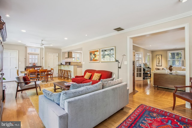 living room featuring ceiling fan, ornamental molding, plenty of natural light, and visible vents