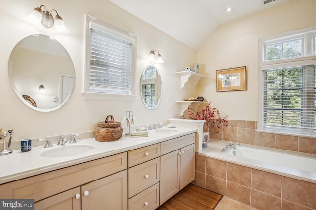 full bath with a sink, double vanity, lofted ceiling, and a garden tub