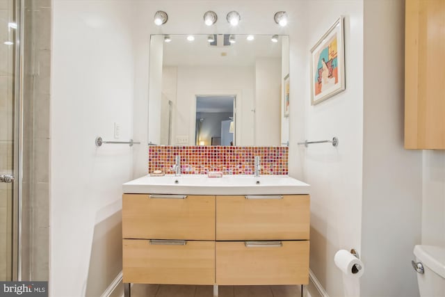 bathroom with a sink, a shower with door, toilet, and decorative backsplash