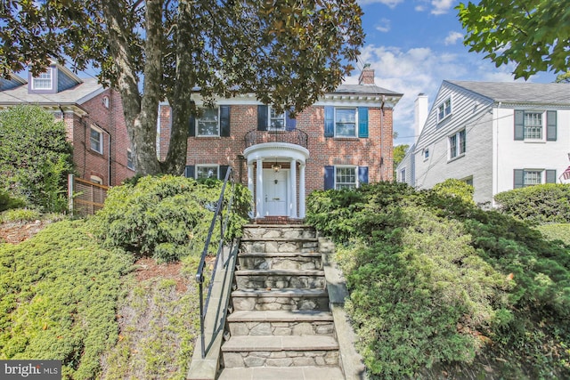 view of front of property featuring a chimney and brick siding