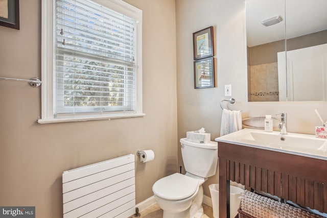 bathroom with vanity, toilet, radiator, and baseboards