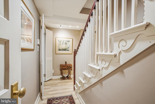 hallway featuring stairs, baseboards, and light wood-type flooring