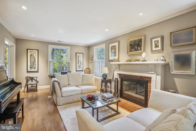living area featuring recessed lighting, baseboards, a brick fireplace, crown molding, and wood finished floors