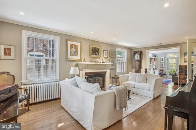 living room with ornamental molding, radiator heating unit, a fireplace, and recessed lighting