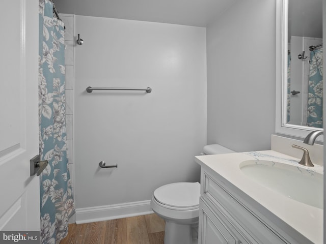 bathroom with toilet, wood finished floors, vanity, curtained shower, and baseboards