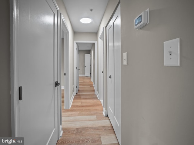 hallway featuring light wood finished floors and baseboards