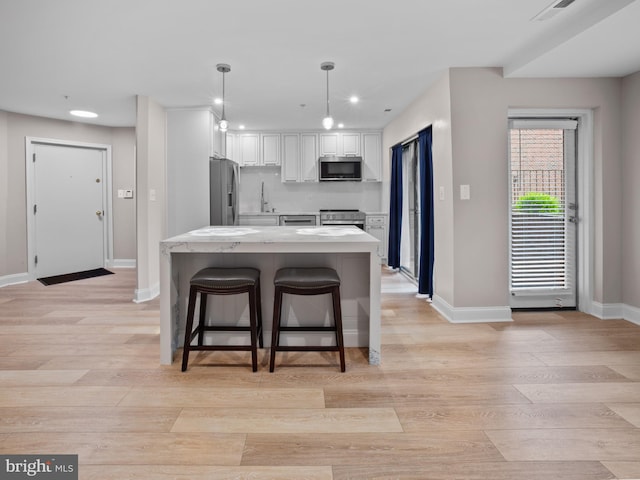 kitchen with stainless steel appliances, recessed lighting, light wood-style flooring, white cabinets, and baseboards
