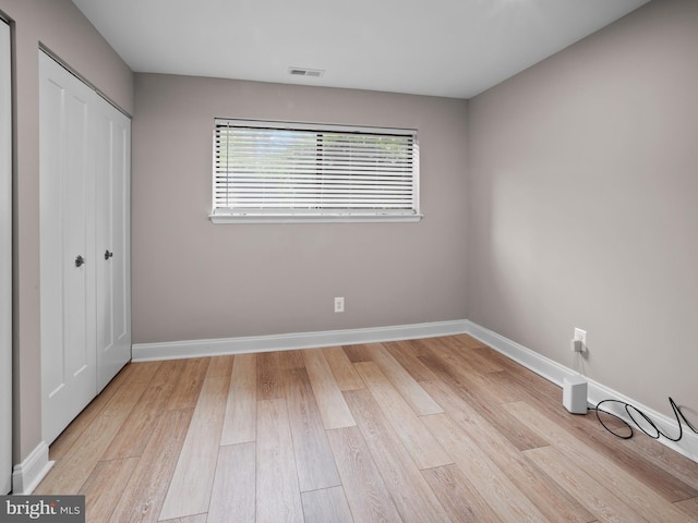 unfurnished bedroom with light wood-style flooring, baseboards, a closet, and visible vents