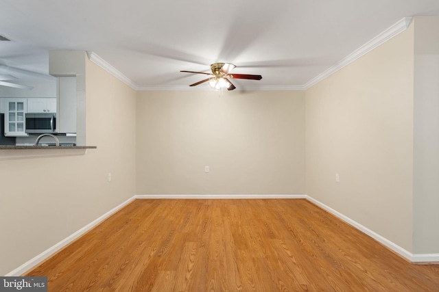 unfurnished room with ceiling fan, ornamental molding, baseboards, and light wood finished floors