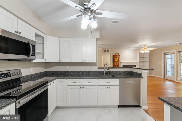 kitchen with ceiling fan, stainless steel appliances, a peninsula, a sink, and white cabinetry