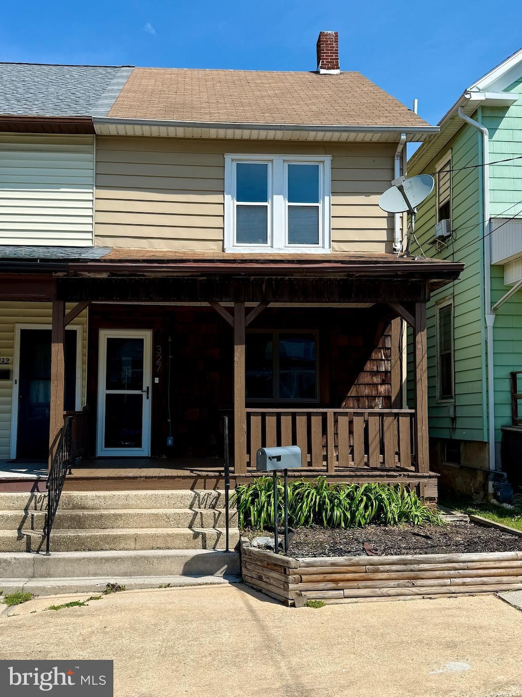 view of front facade featuring a porch, a shingled roof, and a chimney