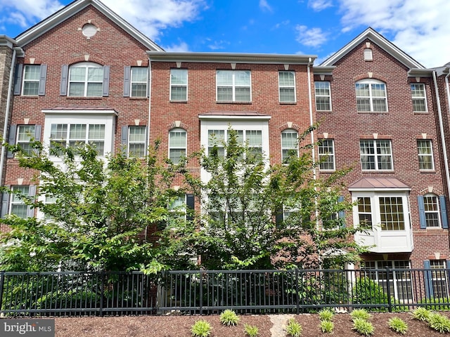 view of front of house featuring brick siding and fence