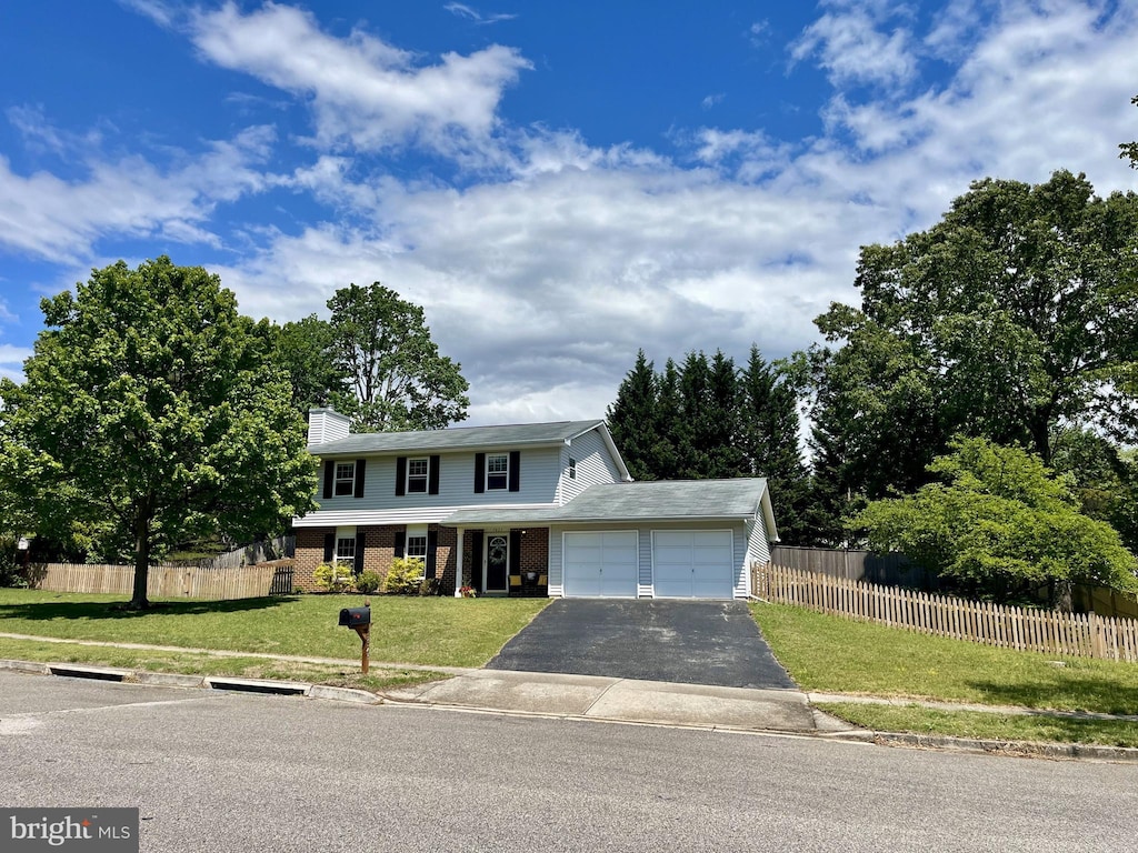 traditional home with driveway, a garage, fence, and a front yard