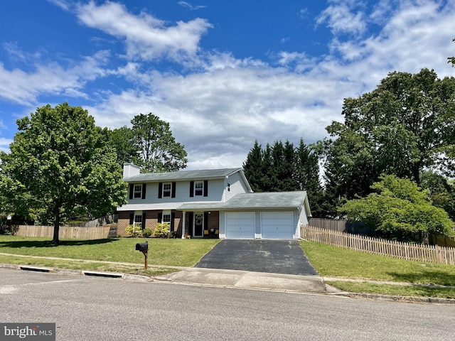 traditional home with driveway, a garage, fence, and a front yard