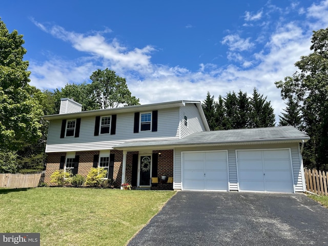 traditional-style house featuring a garage, fence, a front yard, brick siding, and driveway