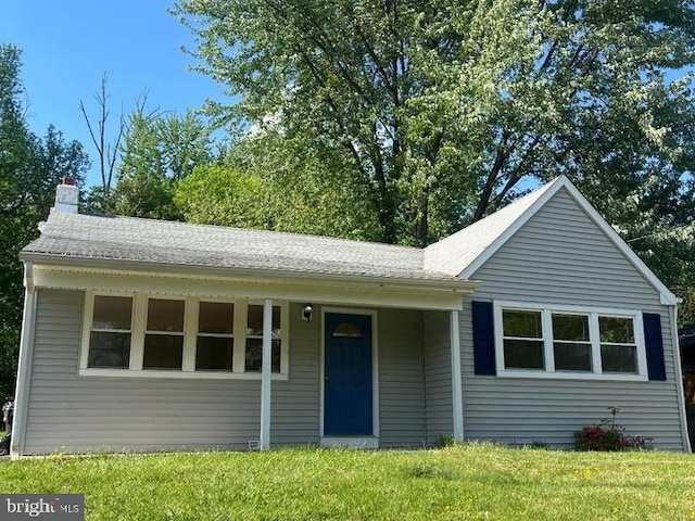 single story home with a chimney and a front yard