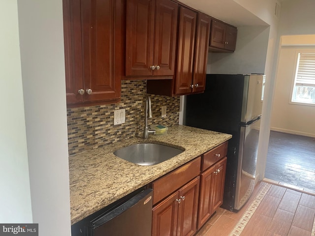 kitchen featuring backsplash, light stone counters, a sink, and dishwasher