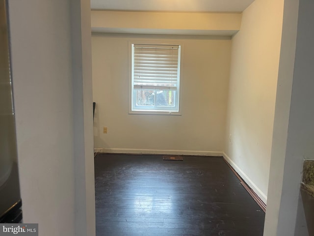 spare room featuring baseboards and dark wood-style floors