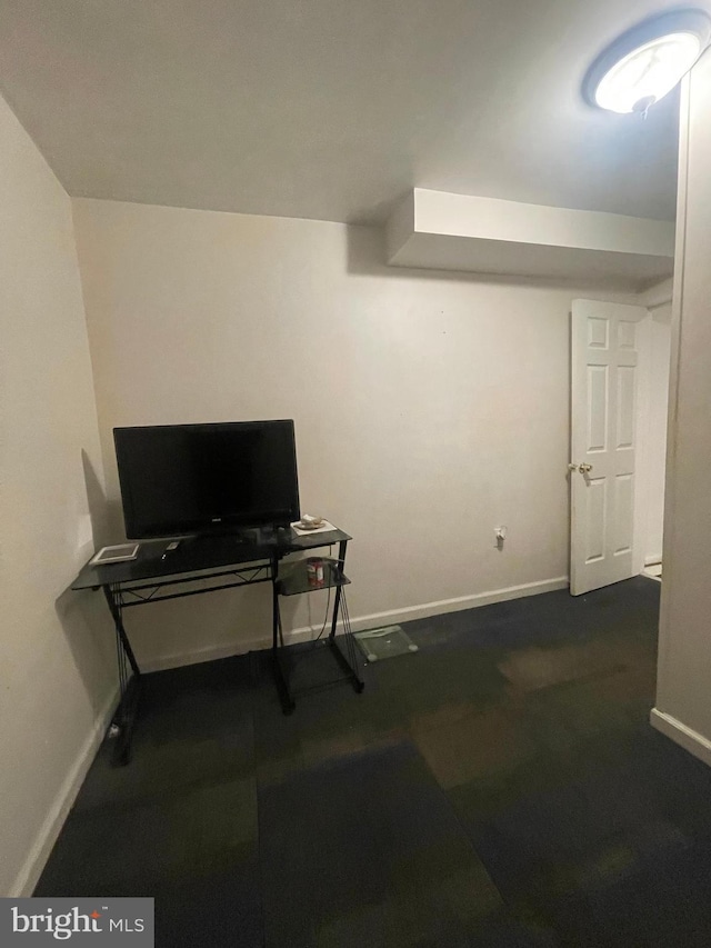 finished below grade area with baseboards and dark colored carpet