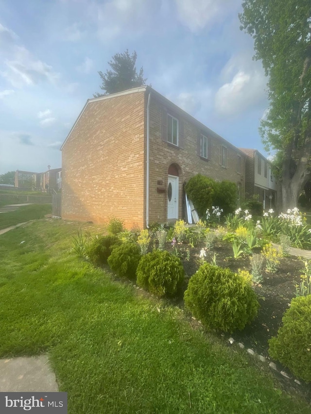 view of side of property featuring brick siding and a yard
