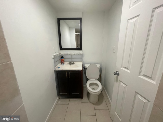 bathroom with vanity, tile patterned flooring, baseboards, and toilet