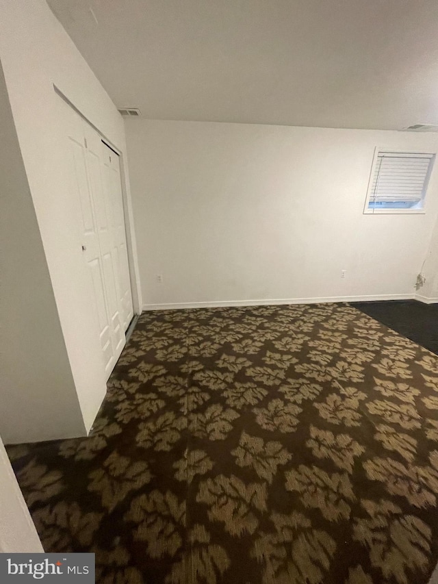 interior space with visible vents, dark carpet, and a closet