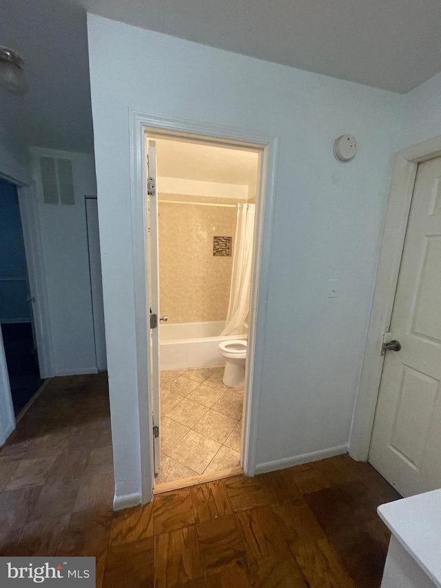 bathroom featuring toilet, baseboards, visible vents, and shower / bath combination with curtain