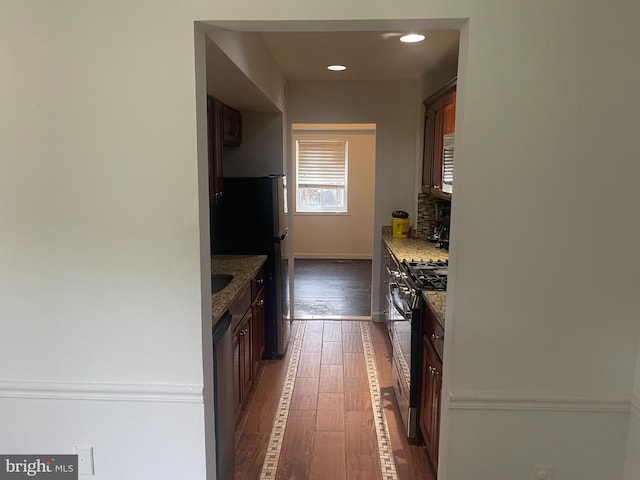 kitchen featuring decorative backsplash, light stone countertops, appliances with stainless steel finishes, and dark wood-style floors