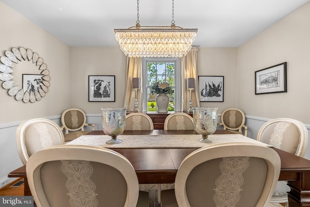 dining area with a chandelier and a wainscoted wall