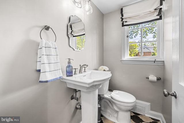 half bathroom featuring toilet and baseboards