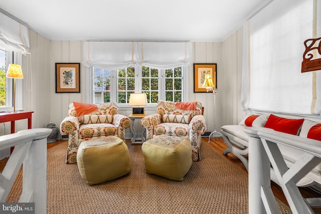 living area with wood finished floors, healthy amount of natural light, and ornamental molding