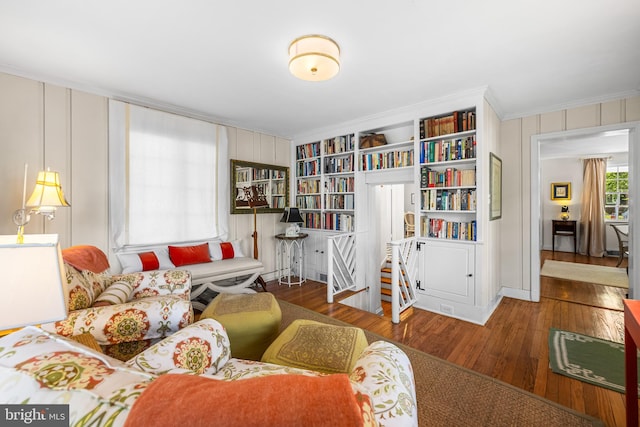 sitting room with ornamental molding and wood finished floors
