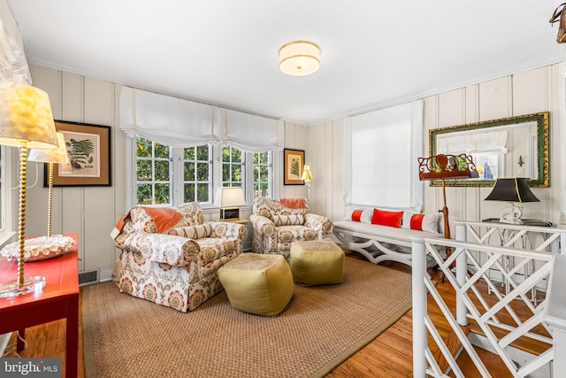 sitting room with wood finished floors and a decorative wall