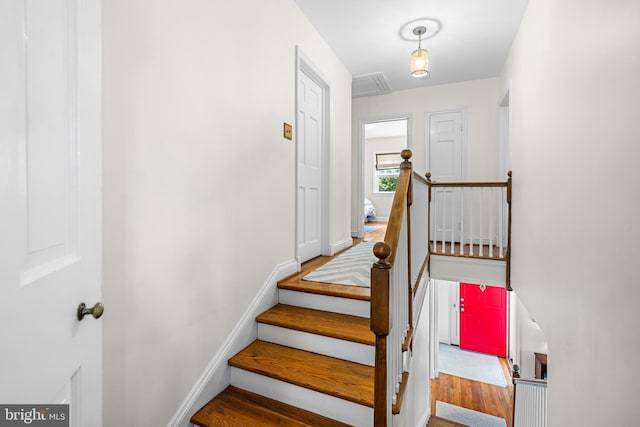 staircase featuring attic access, baseboards, and wood finished floors