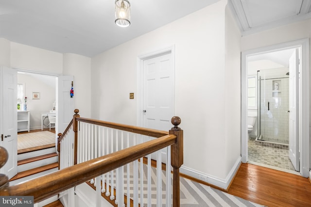 corridor featuring an upstairs landing, wood finished floors, and baseboards