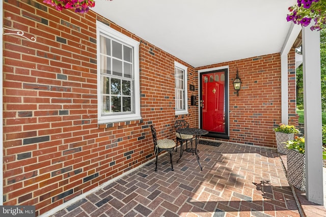 property entrance featuring brick siding and a porch