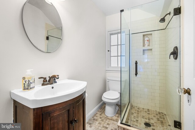 bathroom featuring toilet, a stall shower, vanity, baseboards, and tile patterned flooring