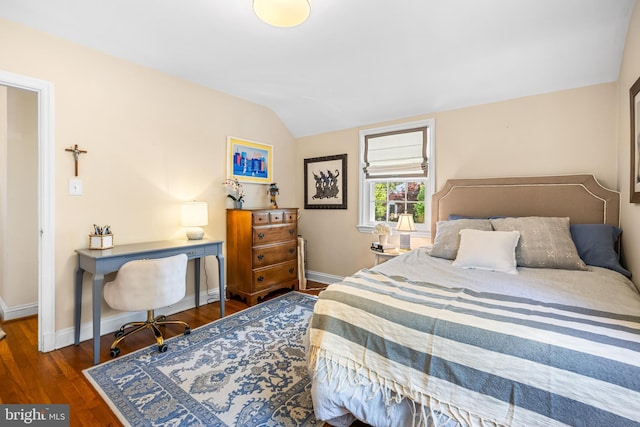 bedroom with vaulted ceiling, baseboards, and wood finished floors