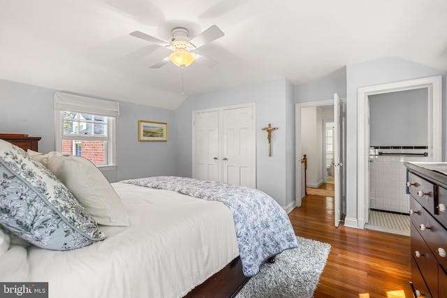 bedroom featuring dark wood-style floors, vaulted ceiling, baseboards, a closet, and ceiling fan