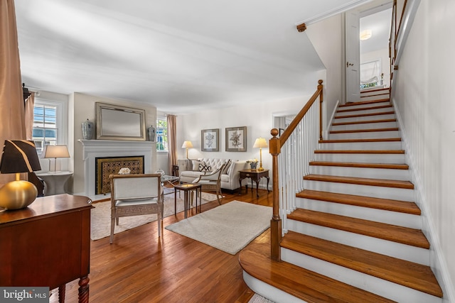 stairway with a fireplace and wood finished floors
