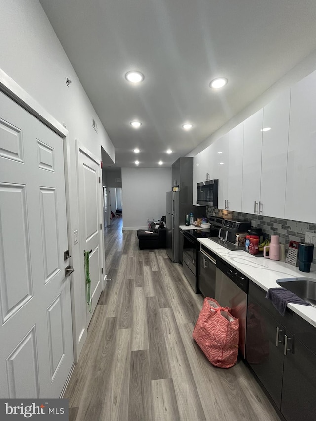kitchen featuring white cabinets, light countertops, light wood-style flooring, stainless steel appliances, and modern cabinets
