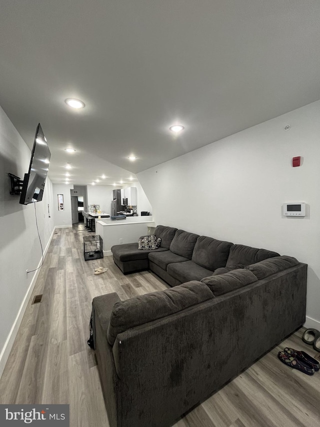 living area featuring light wood-type flooring, baseboards, and visible vents