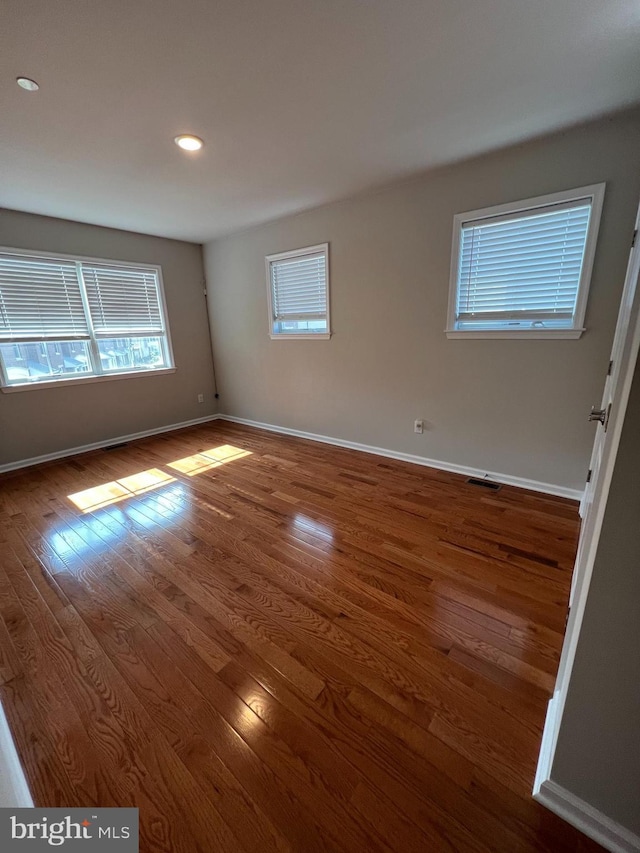 empty room featuring recessed lighting, baseboards, visible vents, and wood finished floors