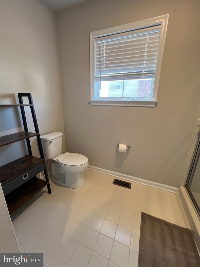 bathroom featuring toilet, a shower with door, visible vents, and baseboards