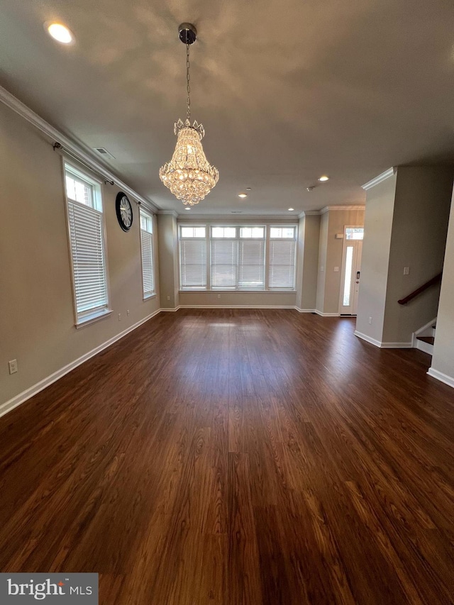 unfurnished living room featuring baseboards, a notable chandelier, ornamental molding, and plenty of natural light