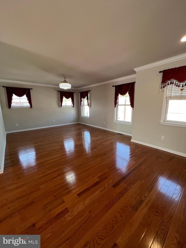 unfurnished living room featuring baseboards, ornamental molding, and wood finished floors