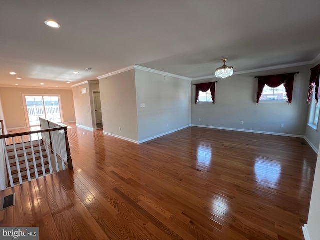 empty room featuring crown molding, baseboards, wood finished floors, and a chandelier